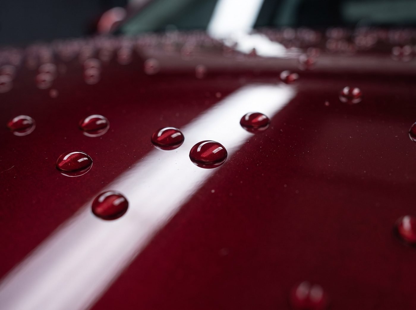 Macro shot of water beading on freshly ceramic-coated dark red car paint